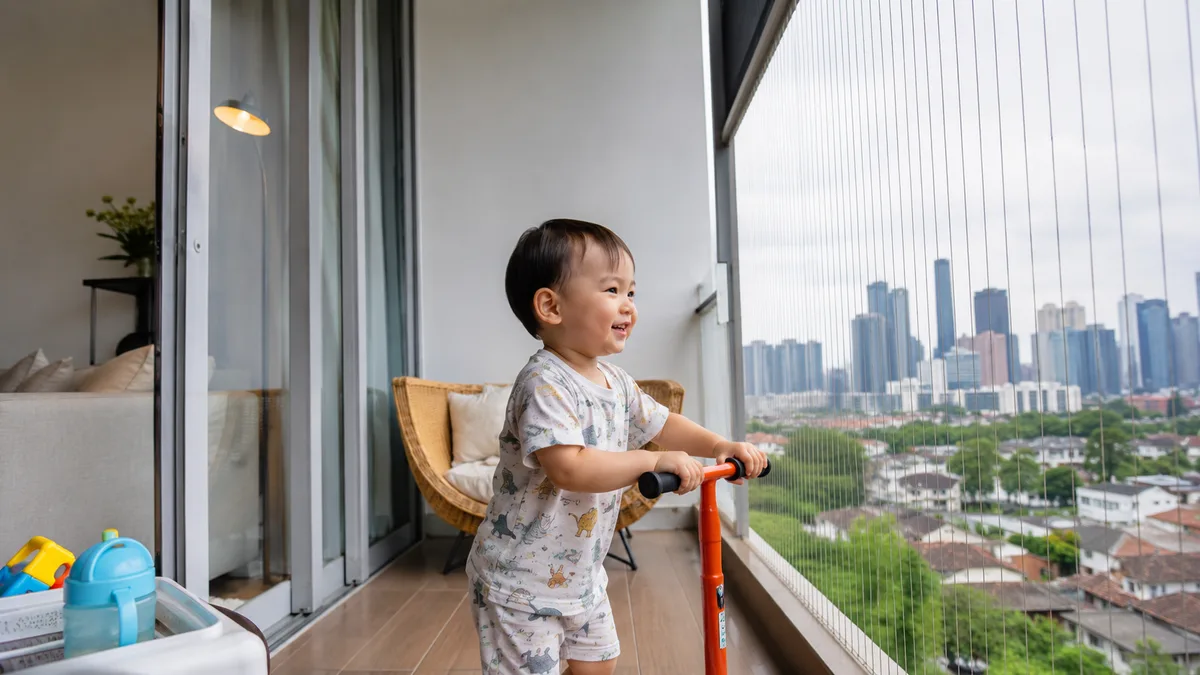 Toddler safely playing near condo balcony protected by invisible grille