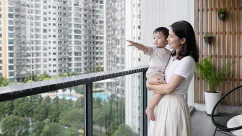 Ibu mendukung bayi di sebelah tingkap balkoni yang dilindungi invisible grille