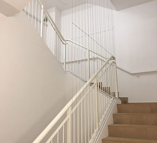 Invisible grill wires closing off an open staircase in a white stairwell